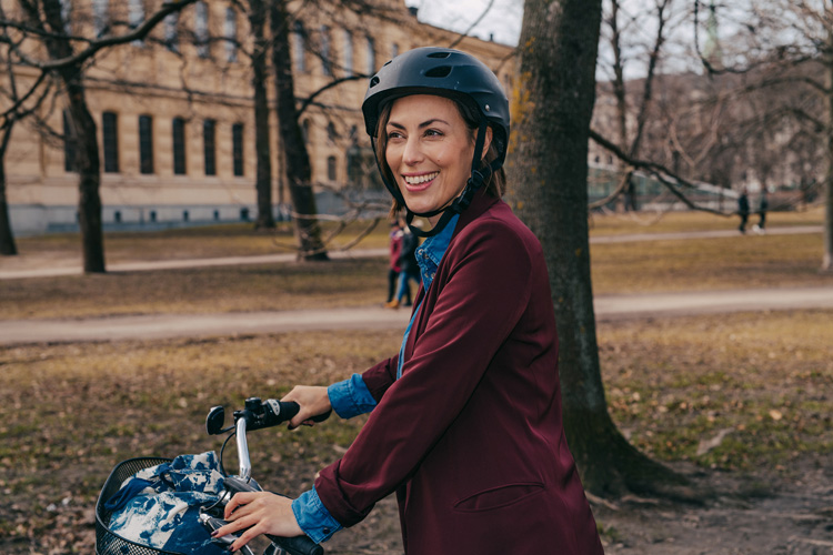 Leende kvinna på cykel i en park.