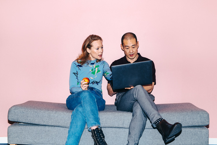 En kvinna och en man sittar och tittar ner i en bärbar dator. 