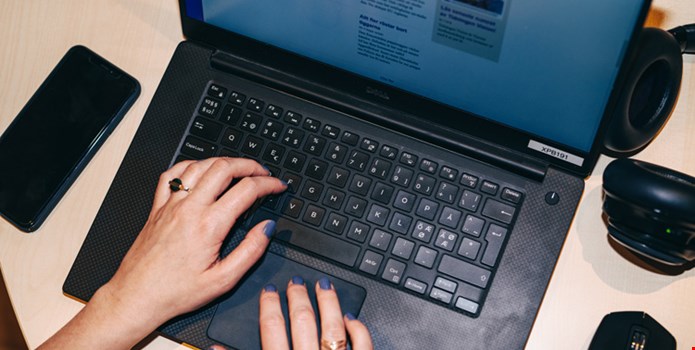 Två händer skriver på tangentbordet till en bärbar dator.