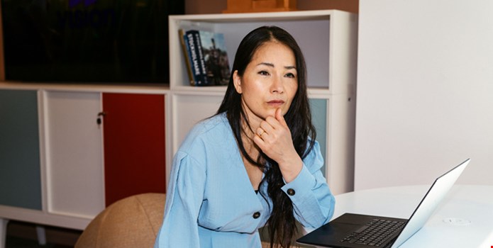Kvinna sitter framför datorn och ser tankfull ut.