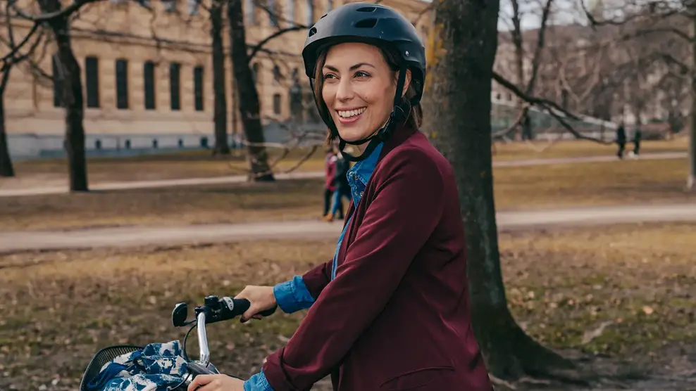 En kvinna med cykelhjälm leder sin cykel.